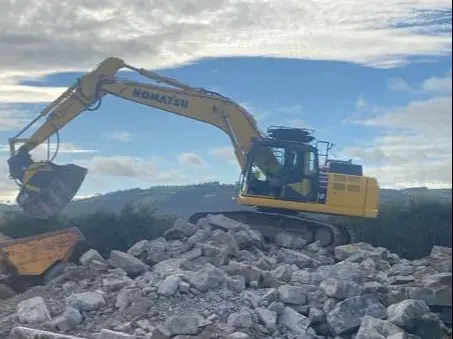 Komatsu excavator with breaker attachment on a rock-breaking site