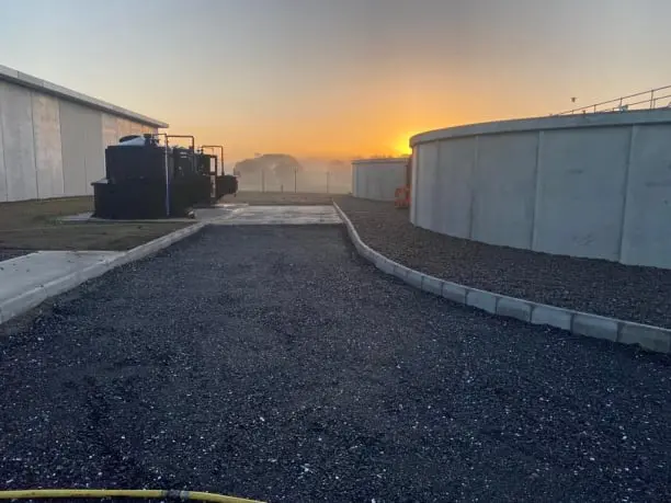 Wastewater treatment tanks with paved access road at sunrise